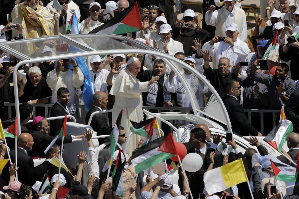 Pope Francis waves to the crowd as he arrives to Manger Square to lead an open-air mass in the West Bank town of Bethlehem