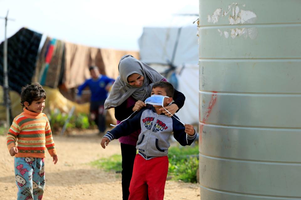 Syrian refugee woman puts a mask on her child in southern Lebanon (REUTERS)