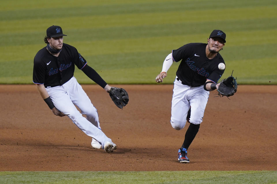 Miami Marlins shortstop Miguel Rojas, right, fields a ball hit by Washington Nationals' Asdrubal Cabrera, who was out at first, as third baseman Brian Anderson watches during the first inning of the second game of a baseball doubleheader, Friday, Sept. 18, 2020, in Miami. (AP Photo/Wilfredo Lee)