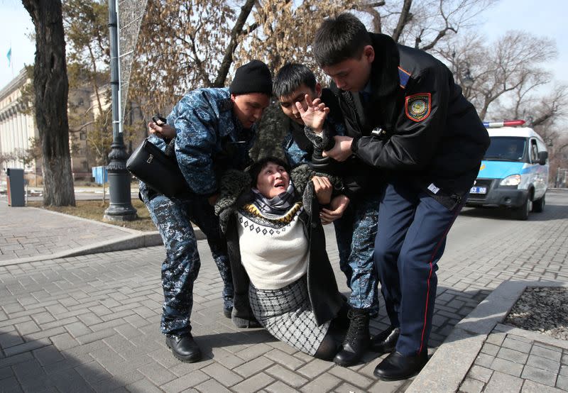 Kazakh law enforcement officers detain a woman during a rally held by opposition supporters in Almaty