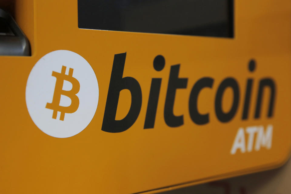 FILE - In this Dec. 21, 2017 file photo, a Bitcoin logo is shown is displayed on an ATM in Hong Kong, Thursday, Dec. 21, 2017. Tesla says it has invested more than $1 billion in Bitcoin and will accept the digital currency as payment for its electric vehicles. In a regulatory filing Monday, Feb. 8, 2021, Elon Musk’s electric vehicle company said its board approved of the $1.5 billion investment and potentially more in the future. (AP Photo/Kin Cheung, File)