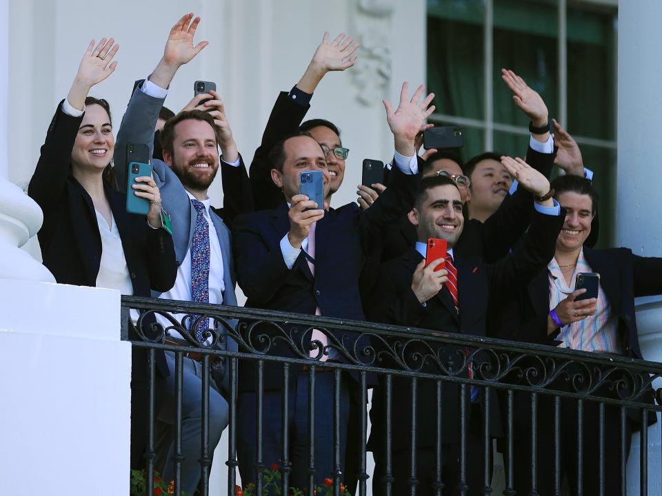 White House staff members wave to U.S. President Joe Biden from a balcony on the south side of the White House as he departs on June 25, 2021 in Washington, DC.