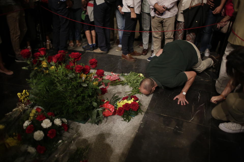 In this Saturday, Oct. 5, 2019 photo, a man kisses the tomb of former Spanish dictator Francisco Franco inside the basilica at the Valley of the Fallen monument near El Escorial, outside Madrid. After a tortuous judicial and public relations battle, Spain's Socialist government has announced that Gen. Francisco Franco's embalmed body will be relocated from a controversial shrine to a small public cemetery where the former dictator's remains will lie along his deceased wife. (AP Photo/Alfonso Ruiz)