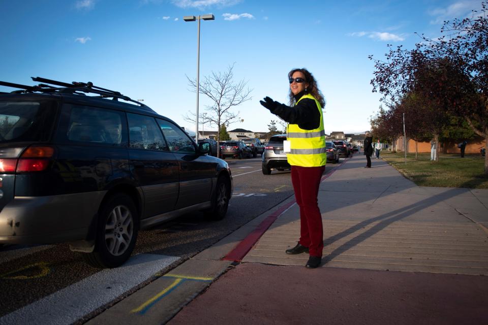 Wendi Grigg, an instructional paraprofessional at Kinard Core Middle School, directs cars dropping off students before the start of the school day at Kinard Core Middle School in Fort Collins on Wednesday, Oct. 13, 2021.