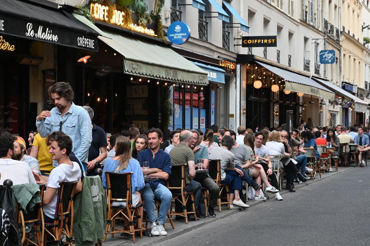 People eat and have drinks at a cafe terrace in the rue de Buci in Paris on June 2, 2020, the day cafes and restaurants reopened in France.