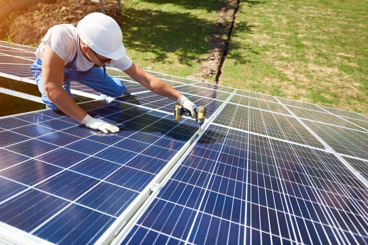 A worker installing solar panels on a roof.