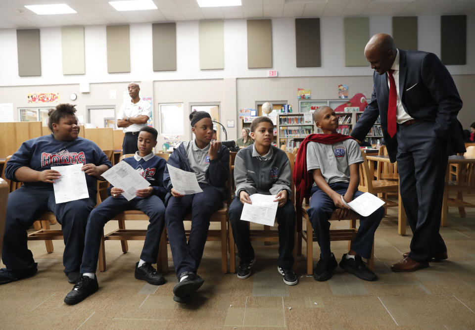 In this Tuesday, Dec. 18, 2018 photo, Jamar McKneely, CEO of InspireNOLA Charter Schools, talks with students at Alice M. Harte Charter School in New Orleans. Charter schools, which are publicly funded and privately operated, are often located in urban areas with large back populations, intended as alternatives to struggling city schools. (AP Photo/Gerald Herbert)