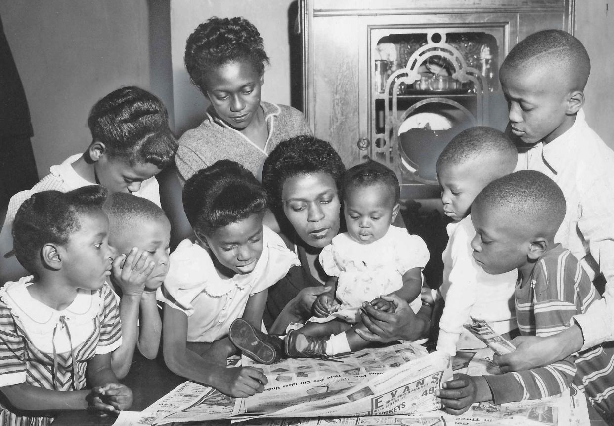 Helen Arnold sits at a table with her nine children Dec. 23, 1955, to look for gift ideas in the Beacon Journal after receiving $100 from a mysterious benefactor in Akron. The kids, from left, are Carla, 3, Gary, 5, Mona, 9, Gale, 8, Cathy, 14, Donna, 7 months, Gerald, 2, John, 7, and Royal, 11.