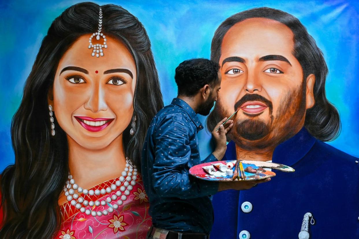 Artist Jagjot Singh Rubal paints portraits of Radhika Merchant, left, and her fiancé, Anant Ambani, son of billionaire Mukesh Ambani, in Amritsar, India, on Wednesday, ahead of the couple's wedding.  (Narinder Nanu/AFP/Getty Images - image credit)