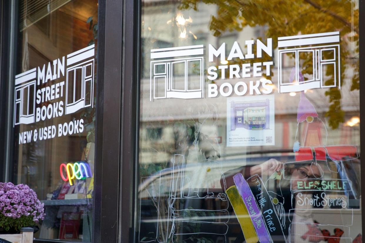 Elizabeth Lincourt, manager of Main Street Books, 426 Main St., draws gnomes on the storefront window's for the holiday season, Thursday, Nov. 18, 2021 in Lafayette.