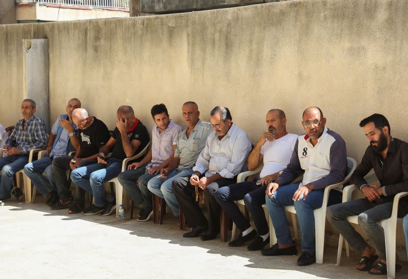 People sit together as they pay condolences for Mustafa Misto, a Lebanese man who was on the migrant boat with his three young children which sank off the Syrian coast on Thursday after sailing from Lebanon