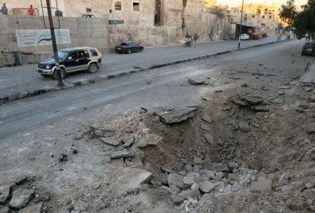 People ride a vehicle past a crater in the rebel-held Qadi Askar neighborhood of Aleppo, Syria, September 26, 2016. REUTERS/Abdalrhman Ismail