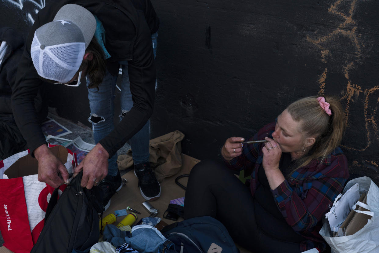 Holly Ferrante, 28, right, smokes fentanyl as her husband, Clark Veater, pack their belongings in Los Angeles, Monday, May 23, 2022. Use of fentanyl, a powerful synthetic opioid that is cheap to produce and is often sold as is or laced in other drugs, has exploded. Because it's 50 times more potent than heroin, even a small dose can be fatal. (AP Photo/Jae C. Hong)