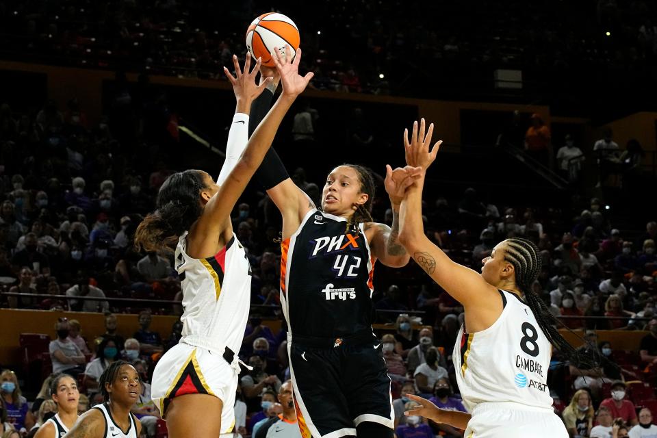 Phoenix Mercury center Brittney Griner (42) drives between Las Vegas Aces forward A'ja Wilson and center Liz Cambage (8) during the first half of a WNBA basketball game Sunday, Oct. 3, 2021, in Phoenix. (AP Photo/Rick Scuteri)