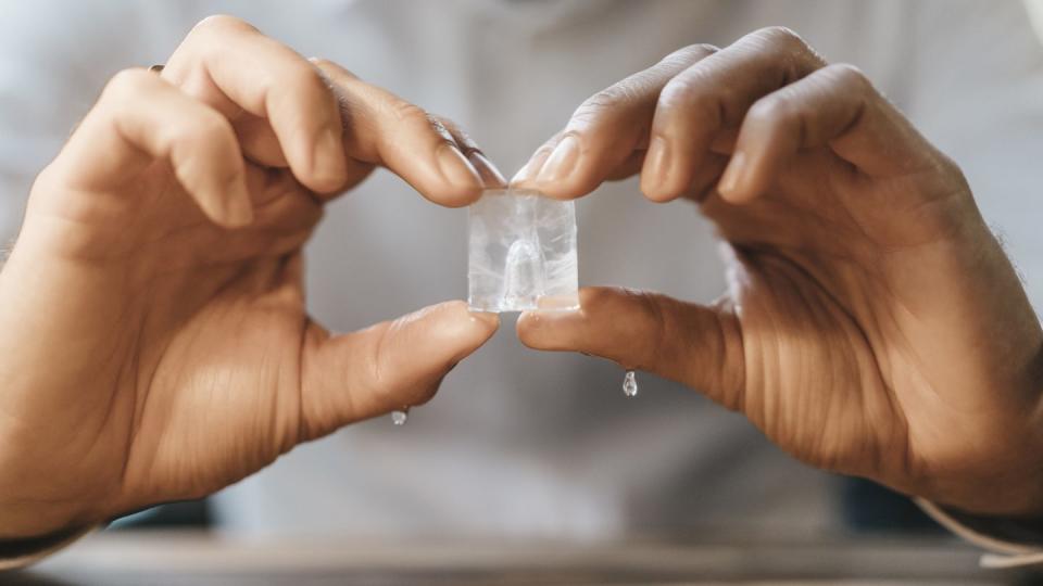 hands of man holding melting ice cube