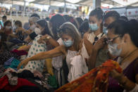 Customers wearing face masks buy clothes for one euro at a stall in a market in Barcelona on Wednesday, July 8, 2020. Spain's northeastern Catalonia region will make mandatory the use of face masks outdoors even when social distancing can be maintained, regional chief Quim Torra announced Wednesday. (AP Photo/Emilio Morenatti)