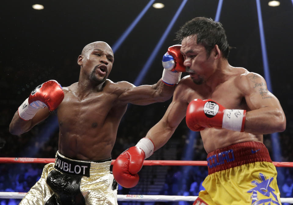 FILE - Floyd Mayweather Jr., left, hits Manny Pacquiao, from the Philippines, during their welterweight title fight on Saturday, May 2, 2015, in Las Vegas. Mayweather Jr. will be inducted into the Boxing Hall of Fame in Canastota, N.Y., on Sunday, June 12, 2022. (AP Photo/Isaac Brekken, File)