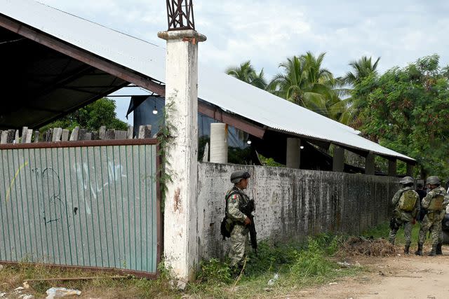 <p>FRANCISCO ROBLES/AFP via Getty</p> Soldiers guard a palenque, or arena, where a cockfight was disrupted by gunfire Saturday night.