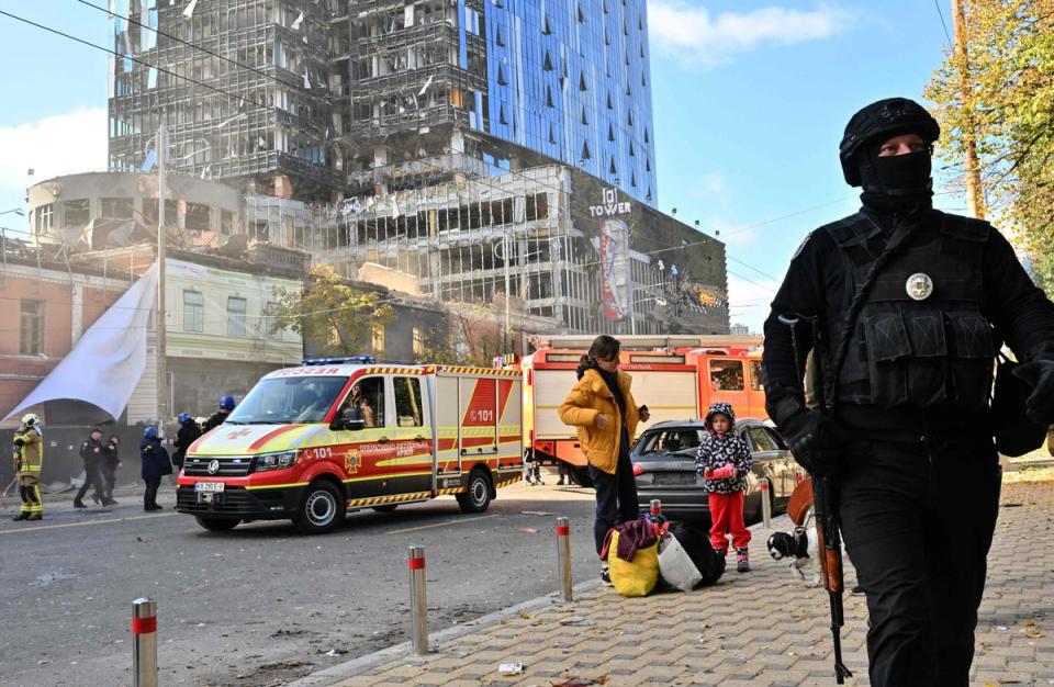 A Ukrainian police officer walks past ambulances parked outside a partially destroyed multistorey office building after (AFP via Getty Images)