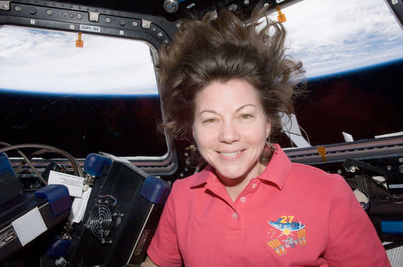 NASA astronaut Cady Coleman is seen inside the Cupola of the International Space Station. Earth's horizon and the blackness of space are visible through the windows.