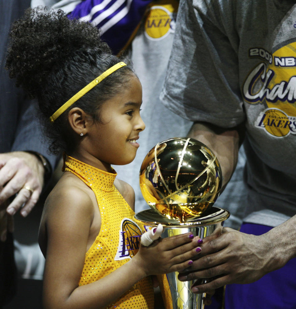 In this June 14, 2009, photo, Los Angles Lakers guard Kobe Bryant's daughter Gianna holds her father's MVP trophy after the Lakers 99-86 defeat of the Orlando Magic in Game 5 of the NBA Finals at Amway Arena in Orlando. Bryant, his 13-year-old daughter Gianna and several others are dead after their helicopter went down in Southern California on Sunday, Jan. 26, 2020. (Stephen M. Dowell/Orlando Sentinel via AP)