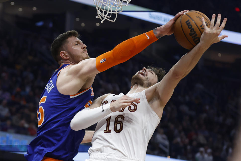 New York Knicks center Isaiah Hartenstein (55) blocks a shot by Cleveland Cavaliers forward Cedi Osman (16) during the first half of an NBA basketball game Friday, March 31, 2023, in Cleveland. (AP Photo/Ron Schwane)