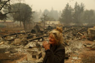 FILE - In this Nov. 9, 2018 photo, Cathy Fallon reacts as she stands near the charred remains of her home in Paradise, Calif. "I'll be darned if I'm gonna let those horses burn in the fire" said Fallon, who stayed on her property to protect her 14 horses, "It has to be true love." (AP Photo/John Locher, File)