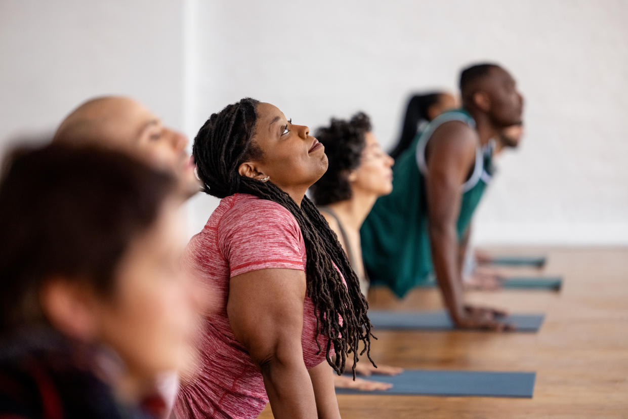 Group of men and women practicing yoga lessons. Diverse group of people in sportswear doing stretching yoga workouts in a fitness studio.