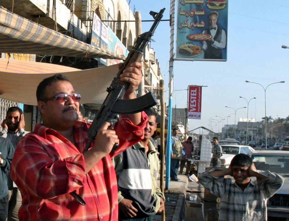 AN IRAQI BOY COVERS HIS EARS WHILE HIS FATHER FIRES IN THE AIR FOLLOWING ARRESTING OF SADDAM HUSSEIN IN BASRA.  An Iraqi boy covers his ears while his father fire machinegun in the air following arresting of ousted Iraqi ruler Saddam Hussein in the southern city of Basra, some 600 km of Baghdad, December 14, 2003. Two car bombs exploded at police stations in and near Baghdad on Monday, killing at least nine people and shattering any hopes of a quick end to violence after the capture of Saddam Hussein. (Picture taken December 14.) REUTERS/Atef Hassan