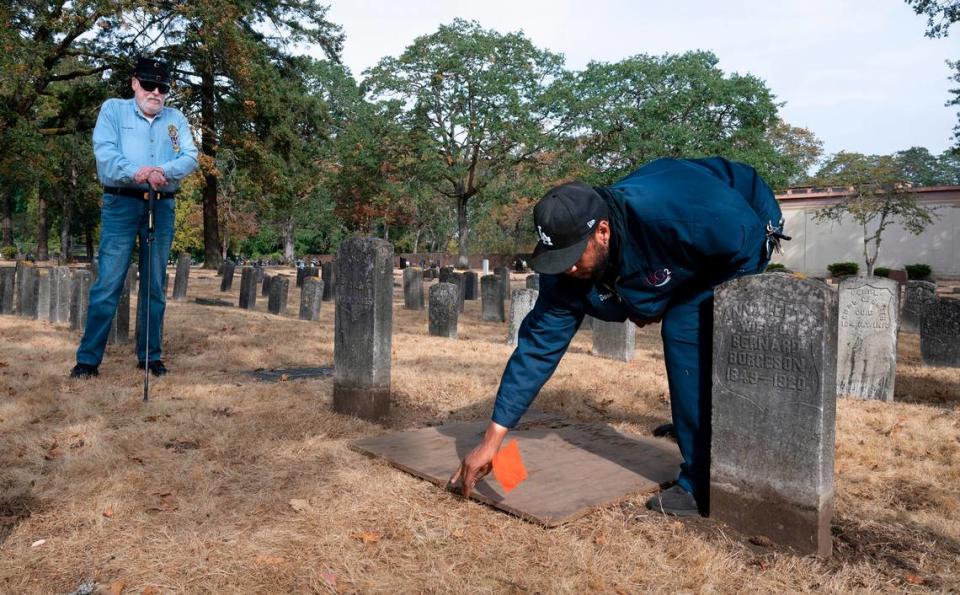 Historian Loran Bures (left) and cemetary foreman David Crutchfield visit the unmarked gravesite of Civil War Navy veteran David Franklin in the Oakwood Hill Cemetary in Tacoma, Washington, on Tuesday, Oct. 4, 2022. An official Veterans Adminstration headstone will be added to the burial site on Saturday.