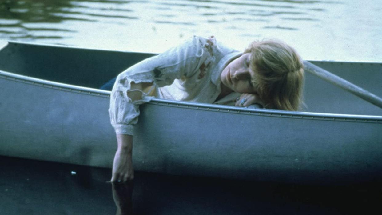 a camper lies in rowboat on a lake in a scene from friday the 13th a good housekeeping pick for best halloween movies