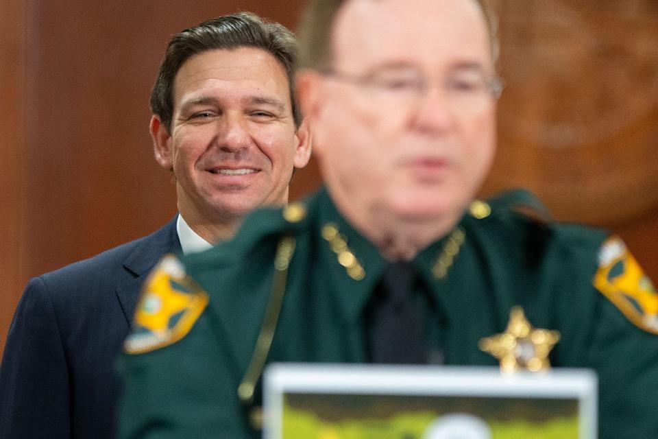 Gov. Ron DeSantis chuckles as Polk County Sheriff Grady Judd shows a meme to the cameras of State Attorney Monique Worrell, who DeSantis announced was suspended during a press conference on Wednesday, Aug. 9, 2023.