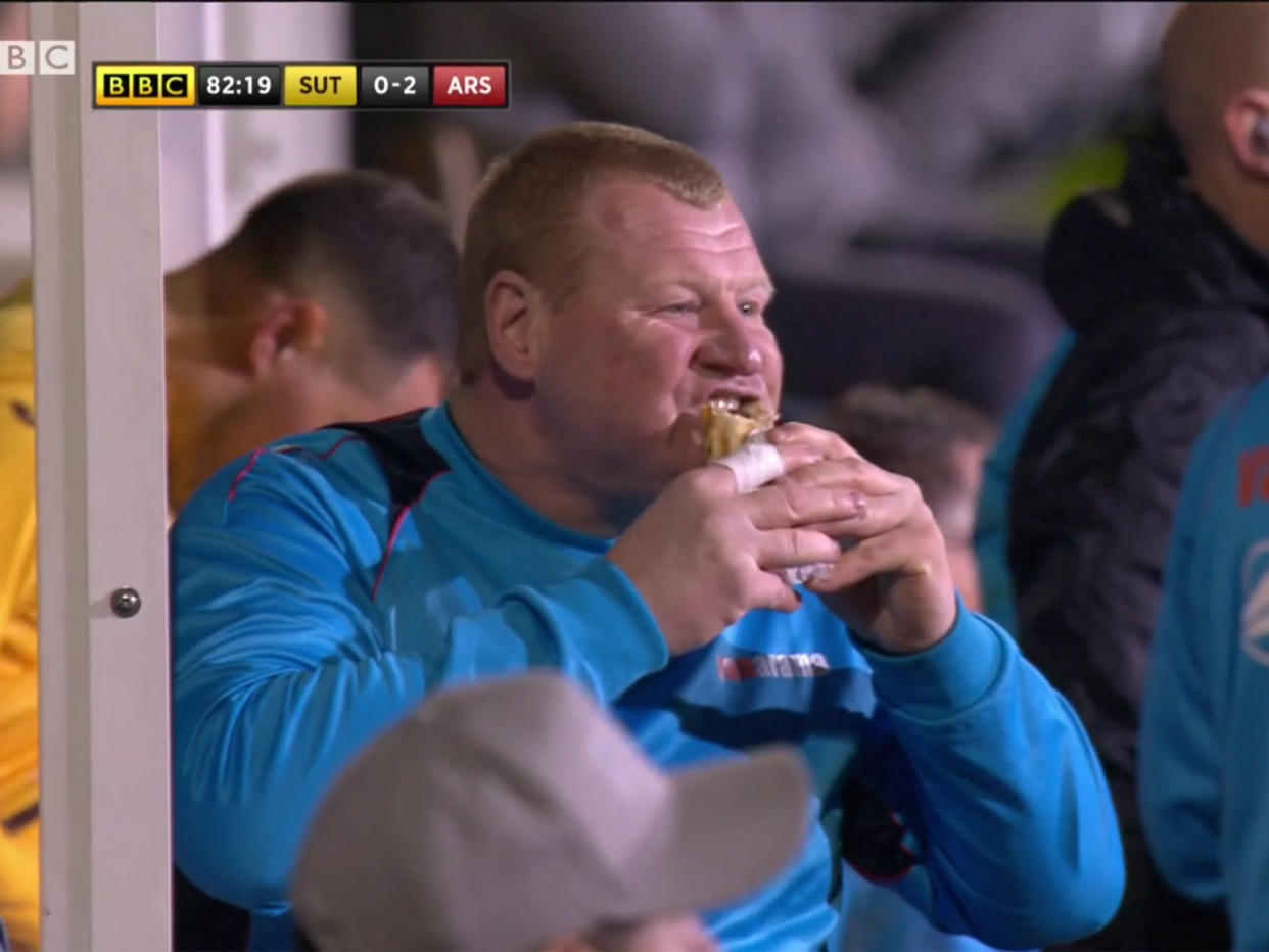 Wayne Shaw tucks into a snack on the sideline during Sutton's FA Cup defeat to Arsenal: BBC Sport