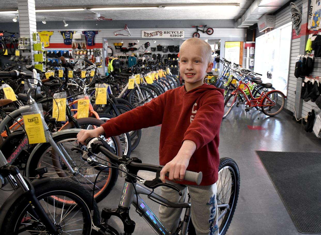 Jordan Owens, 9, who was injured in a Labor Day bicycle accident, picks up his new bike from Ernie’s Bike Shop in North Canton. An anonymous donor bought it for the Plain Township boy in the hope he would live life "with caution but no fear."