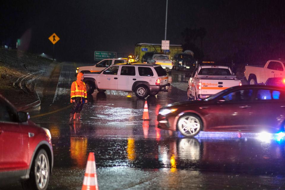 A Caltrans worker directs traffic at a freeway entrance as the U.S. Freeway 101 is closed near Montecito, California