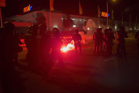 Policemen stand between flares thrown by right wing protesters who are against bringing asylum seekers to an accomodation facility in Heidenau, Germany August 22, 2015. REUTERS/Axel Schmidt