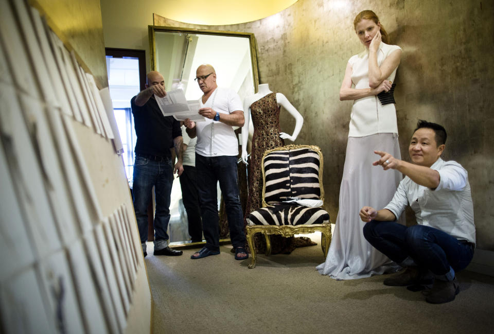 In this Aug. 15, 2013 photo, fashion designer Carmen Marc Valvo, second from left, consults with his communications director Frank Pulice as Valvo's model Taylor Foster, and creative director Il Park, right, look at fashion drawings in a hallway at Valvo's New York studio. Valvo will show his Spring 2014 collection on Sept. 6 at Lincoln Center in New York. (AP Photo/John Minchillo)