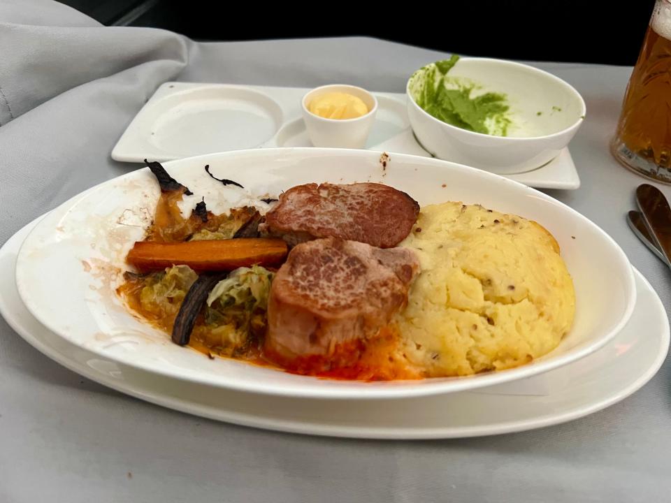 Pork loin with masked potatoes and veggies on a white plate.