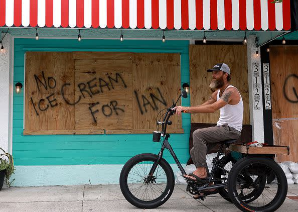 ST. PETERSBURG, FLORIDA - SEPTEMBER 27:  A bicyclist rides past a sign reading, 'No Ice Cream for Ian,' painted on a building that is boarded up for the possible arrival of Hurricane Ian on September 27, 2022 in St Petersburg, Florida. Ian is expected in the Tampa Bay area Wednesday night into early Thursday morning. (Photo by Joe Raedle/Getty Images)