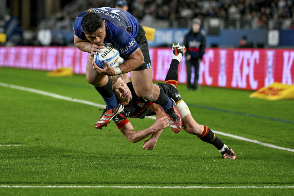 Blues winger Caleb Clarke beats the tackle of Chiefs Damian McKenzie to score a try during the Super Rugby final between the Chiefs and the Blues in Auckland, New Zealand, Saturday, June 22, 2024. (Andrew Cornaga/Photosport via AP)