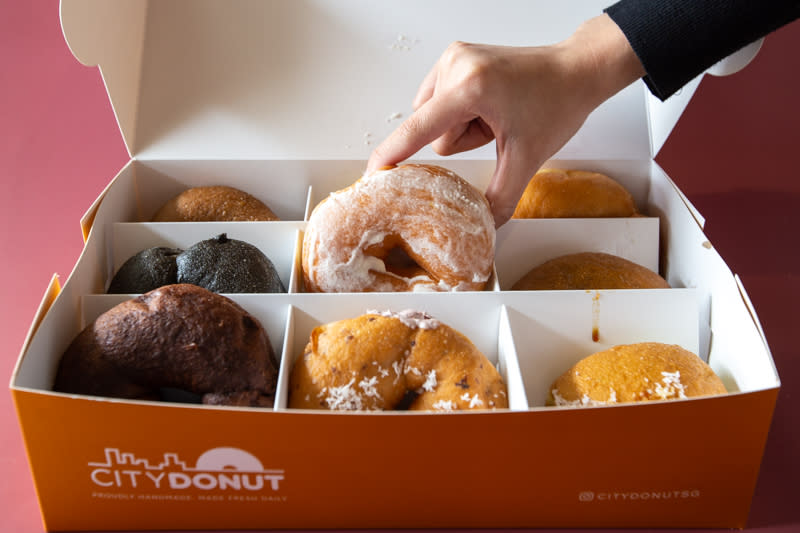 Hand reaching for doughnuts from City Donut box