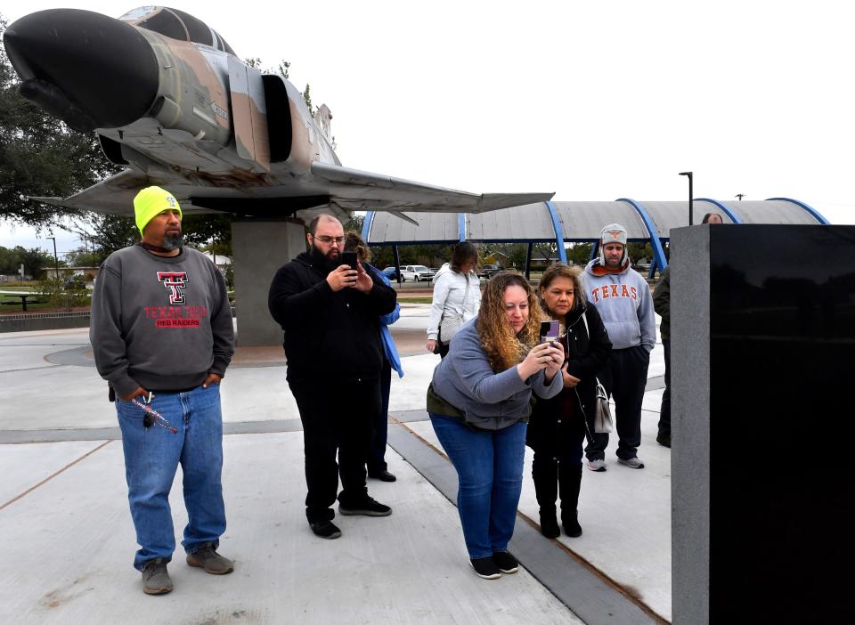 Families and friends photograph the AISD Veterans Memorial Wall at Dyess Elementary School Friday. The first segment of the wall was dedicated during a ceremony with the names of local veterans engraved upon it.