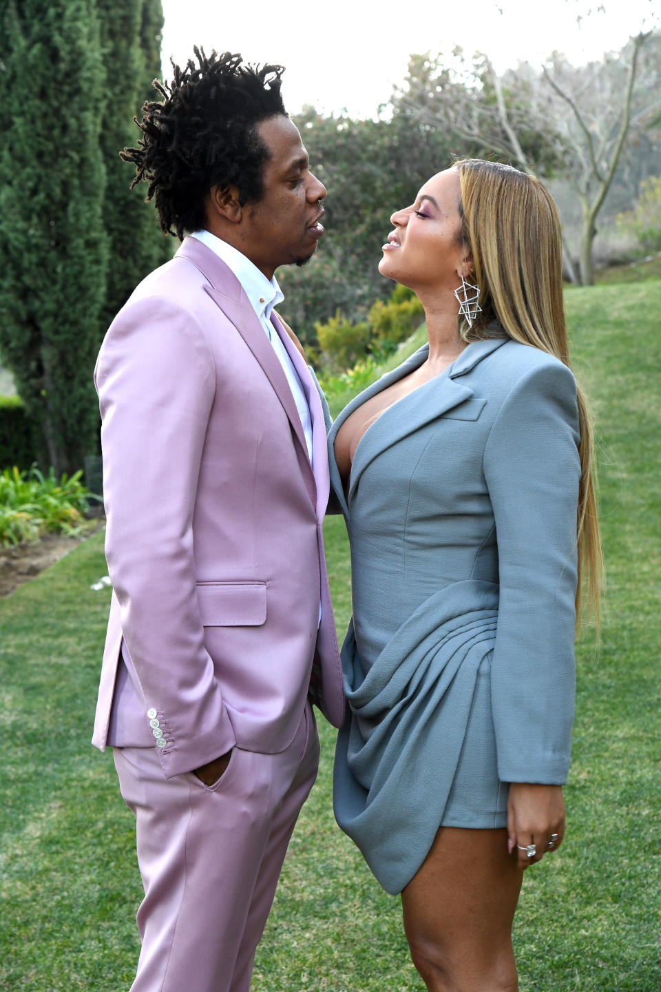 the couple facing each other as they stand outside in grass