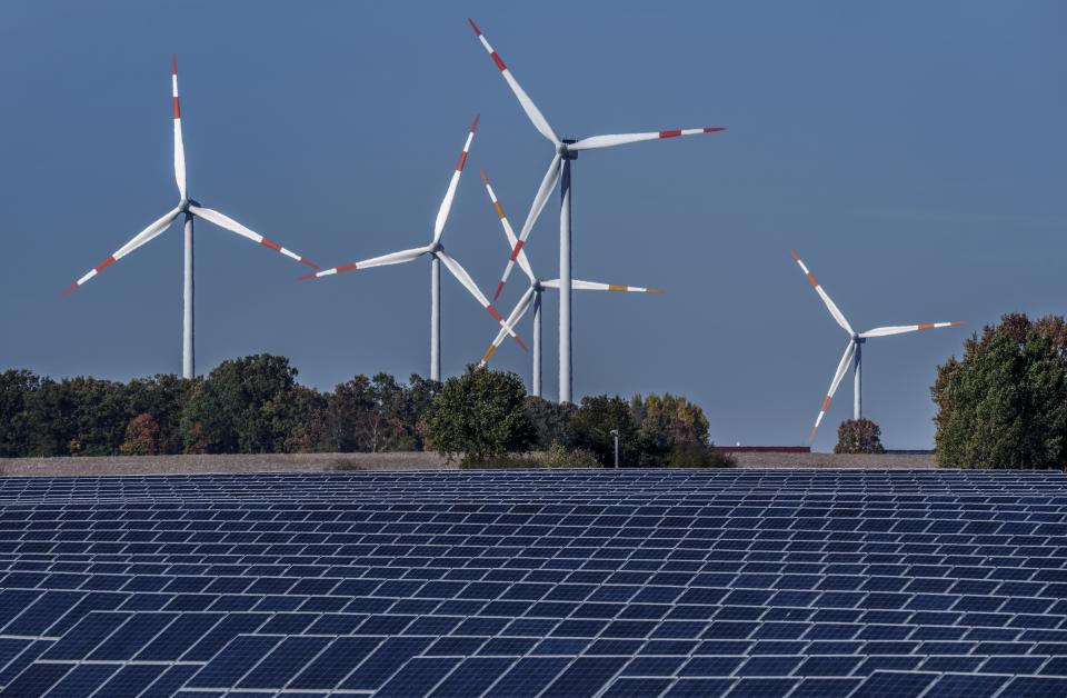 FILE - Wind turbines turn behind a solar farm in Rapshagen, Germany, Oct. 28, 2021. Germany is shutting down its last three nuclear power plants on Saturday, April 15, 2023, as part of an energy transition agreed by successive governments and the price of installing solar and wind energy has dropped significantly in recent years. (AP Photo/Michael Sohn, File)