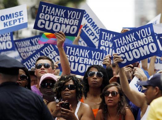 People lining the parade route hold signs thanking New York Governor Andrew Cuomo for the legalization of gay marriage during the Gay Pride Parade in New York June 26, 2011.