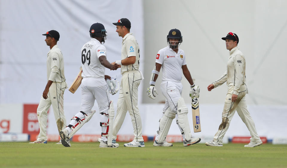 Sri Lanka's Angelo Mathews, second left, and Dimuth Karunaratne, second right, along with New Zealand's Jeet Raval, left, Tim Southee, center, and Gary Nichols leave the field after the play was stopped due to bad light during the first day of the second test cricket match between Sri Lanka and New Zealand in Colombo, Sri Lanka, Thursday, Aug. 22, 2019. (AP Photo/Eranga Jayawardena)