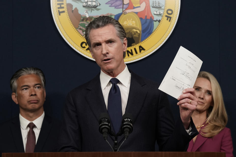 FILE - California Gov. Gavin Newsom displays a bill he just signed that shields abortion providers and volunteers in California from civil judgements from out-of-state courts during a news conference in Sacramento, Calif., on June 24, 2022. Both Newsom, a Democrat and Florida Gov. Ron DeSantis a Republican said their reelection victories were in part because of their commitment to freedom. But the governors have vastly different definitions of what freedom means. (AP Photo/Rich Pedroncelli, File)