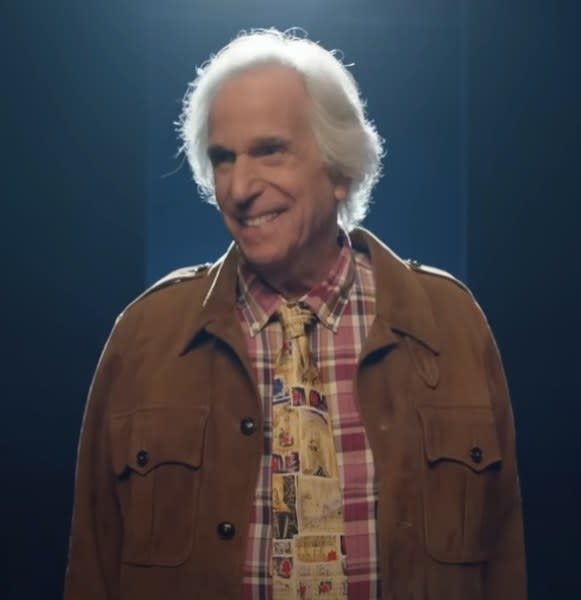 Henry Winkler as Gene Cousineau smiling at someone while standing on stage with a spotlight on him