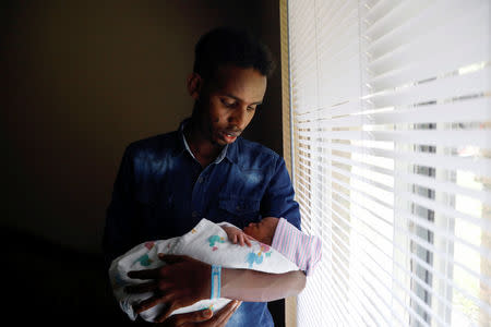 Aden Hussein Hassan holds his daughter Asmo, 2 days, inside their apartment in Columbus, Ohio, U.S., August 8, 2018. REUTERS/Shannon Stapleton