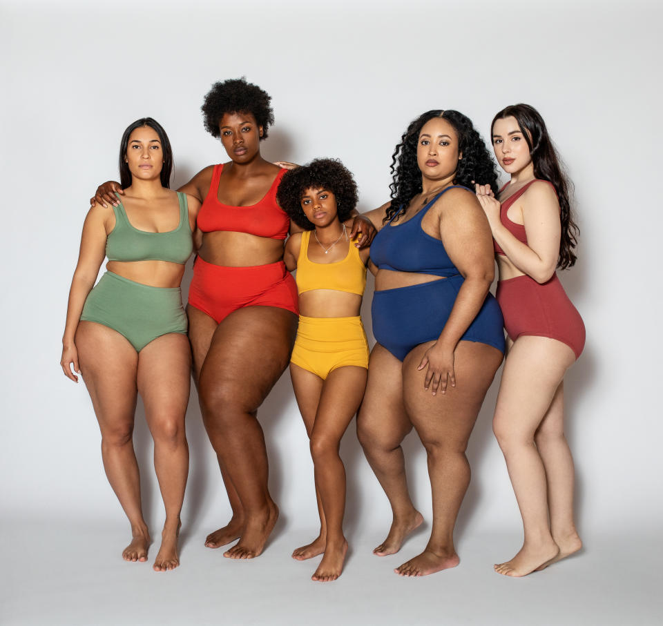 Group of women with different body type in underwear standing together on white background. Full length of multi-ethnic females in lingerie looking at camera. Body positive concept.